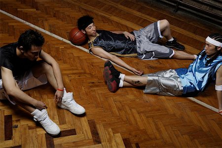 Basketball player relaxing on hardwood floor, elevated view Stock Photo - Premium Royalty-Free, Code: 642-01736041