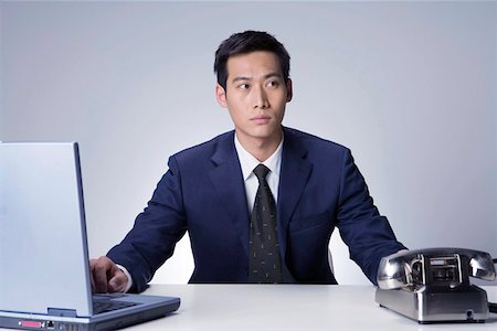 simsearch:642-01734721,k - Young businessman sitting at desk with laptop and telephone Foto de stock - Royalty Free Premium, Número: 642-01736391