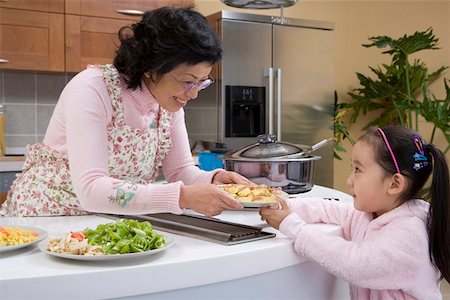 simsearch:642-01736683,k - Grandmother handing dish to granddaughter in kitchen Stock Photo - Premium Royalty-Free, Code: 642-01736636