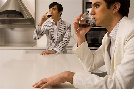 Men sitting at table in kitchen and drinking wine Stock Photo - Premium Royalty-Free, Code: 642-01736698