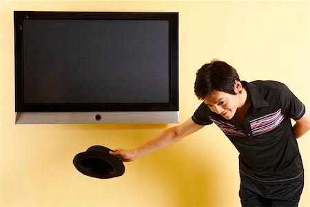 Fashionable young man bowing in front of TV Stock Photo - Premium Royalty-Free, Code: 642-01736857
