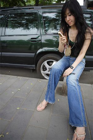 Young woman holding cellphone in front of jeep Stock Photo - Premium Royalty-Free, Code: 642-01736892