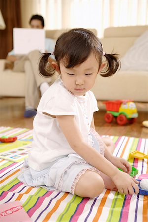 Daughter playing with toys while man sitting on sofa and using laptop Stock Photo - Premium Royalty-Free, Code: 642-01736930