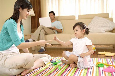 simsearch:693-03305063,k - Young woman playing with daughter while man sitting on sofa using laptop Stock Photo - Premium Royalty-Free, Code: 642-01736931