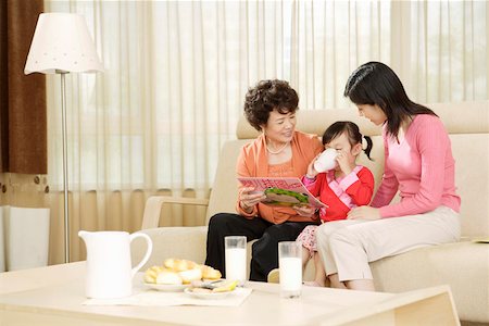 Grandmother and mother holding book while daughter drinking Stock Photo - Premium Royalty-Free, Code: 642-01736947