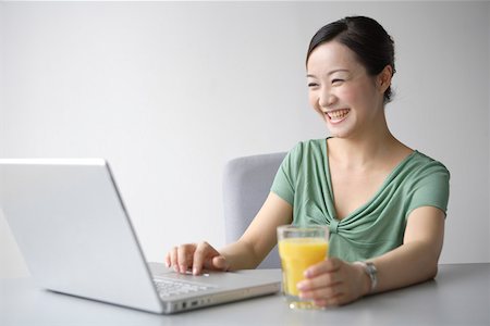 simsearch:642-01737135,k - Young woman playing laptop and smiling with beverage Stock Photo - Premium Royalty-Free, Code: 642-01737053