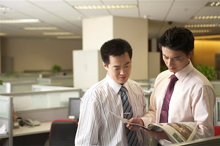 Businessmen looking at a magazine in an office Stock Photo - Premium Royalty-Free, Code: 642-01737514