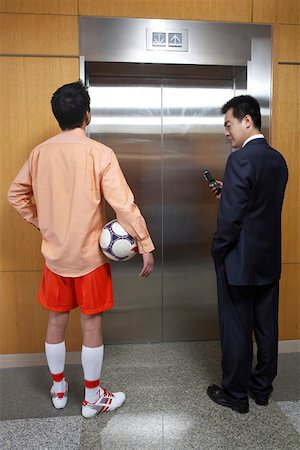 people shocked on phones - Two young men standing in front of lift Stock Photo - Premium Royalty-Free, Code: 642-01737533