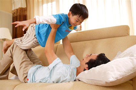 Jeune homme jouant avec l'enfant couché sur le canapé Photographie de stock - Premium Libres de Droits, Code: 642-01737567