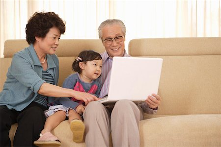 Senior couple playing laptop with daughter in sofa Stock Photo - Premium Royalty-Free, Code: 642-01737574