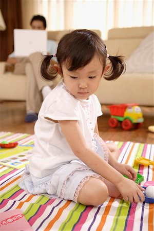 Daughter playing with toys while man sitting on sofa and using laptop Stock Photo - Premium Royalty-Free, Code: 642-01737572