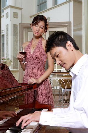 Young man playing piano while woman listening and holding wine glass Stock Photo - Premium Royalty-Free, Code: 642-01737635