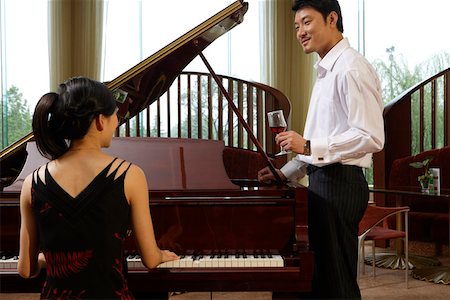 Young man standing near pianist in restaurant and holding wine glass Stock Photo - Premium Royalty-Free, Code: 642-01737640