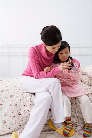 Mother helping her daughter to set alarm on the timepiece Stock Photo - Premium Royalty-Free, Code: 642-01732736