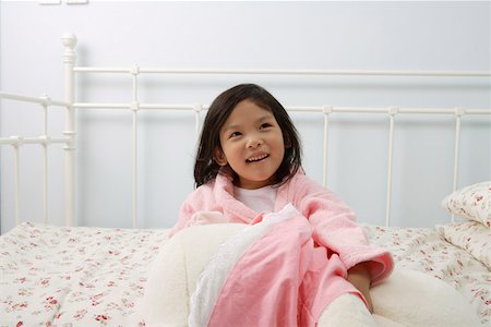simsearch:642-01732733,k - Jeune fille assise sur un lit dans la chambre à coucher, en levant, souriant Photographie de stock - Premium Libres de Droits, Code: 642-01732730