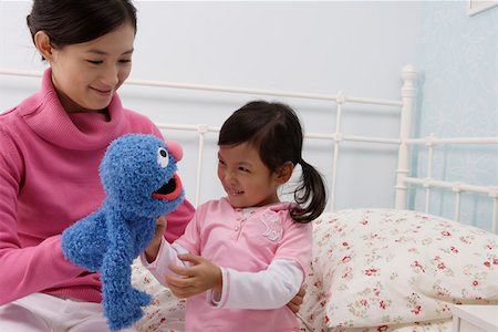 Mother and daughter playing with a puppet in the bedroom Stock Photo - Premium Royalty-Free, Code: 642-01732746