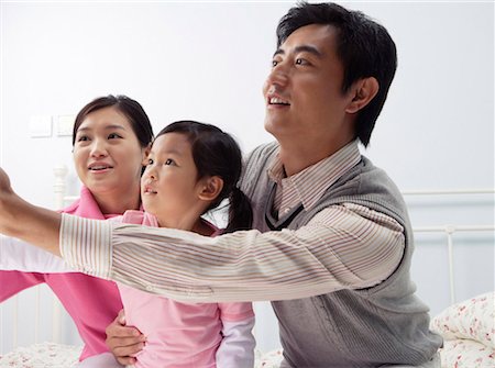 simsearch:642-01732852,k - Young couple playing with their daughter in the bedroom, looking away Stock Photo - Premium Royalty-Free, Code: 642-01732749