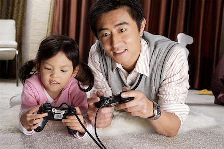simsearch:642-01732852,k - Father and daughter lying on carpet playing video game Stock Photo - Premium Royalty-Free, Code: 642-01732764