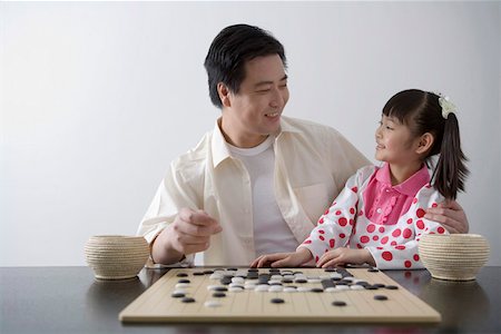 simsearch:642-01732852,k - Young man and daughter playing weiqi game board, smiling Stock Photo - Premium Royalty-Free, Code: 642-01732856