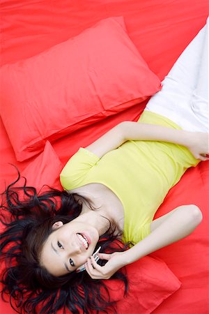 simsearch:642-01734897,k - Young woman lying on bed, using mobile phone, overhead view Stock Photo - Premium Royalty-Free, Code: 642-01732886