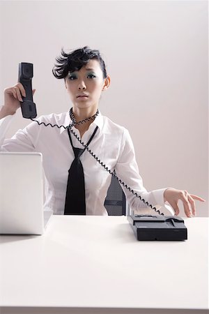Portrait of businesswoman with phone cord around neck Stock Photo - Premium Royalty-Free, Code: 642-01733001
