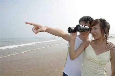 Woman using binoculars, man pointing Stock Photo - Premium Royalty-Free, Code: 642-01733065