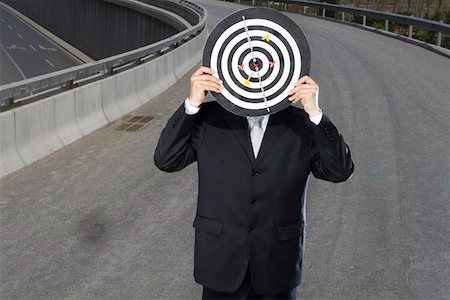 Man holding dartboard in front of face on an overpass Fotografie stock - Premium Royalty-Free, Codice: 642-01733310