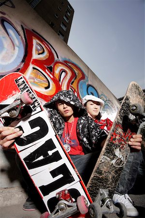 Young couple crouching by graffiti wall with skateboards, portrait Stock Photo - Premium Royalty-Free, Code: 642-01733387