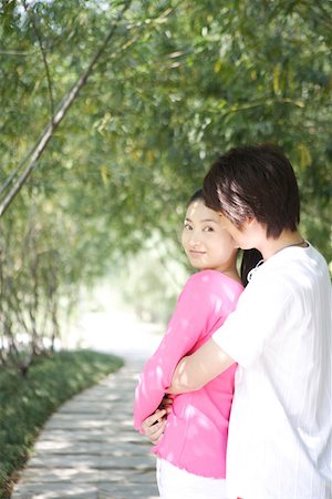 Young man embracing woman, smiling, portrait Stock Photo - Premium Royalty-Free, Code: 642-01733440