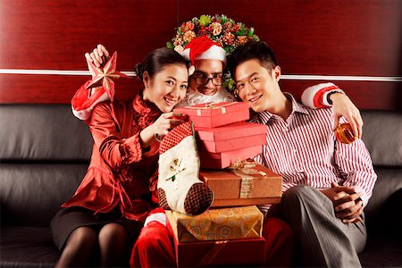 Santa Claus sitting and embracing young lovers behind gifts Stock Photo - Premium Royalty-Free, Code: 642-01733500