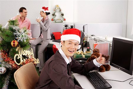 party office - Portrait of a young man gesturing by computer with friends enjoying in the background Stock Photo - Premium Royalty-Free, Code: 642-01733544