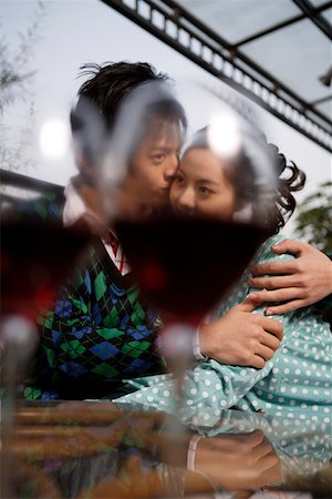 simsearch:642-01737214,k - Young couple embracing with wineglasses in the foreground Stock Photo - Premium Royalty-Free, Code: 642-01733636