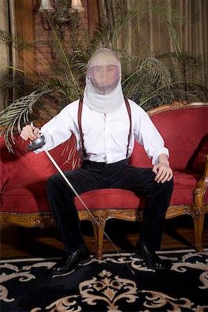 sword - one fashionable man sitting on the sofa with sword in his hand and a mask on his face Stock Photo - Premium Royalty-Free, Code: 642-02004876