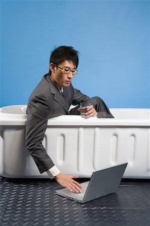 a business man sitting in the bath and seeing the lip-top Stock Photo - Premium Royalty-Free, Code: 642-02005928