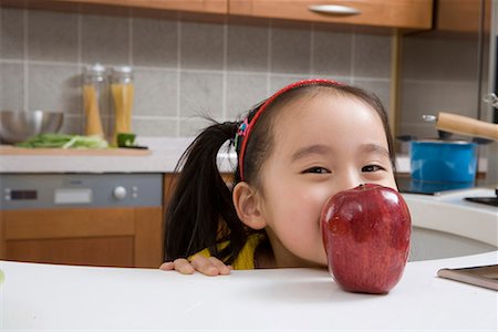 a girl in the kitchen eating apple Stock Photo - Premium Royalty-Free, Code: 642-02006708