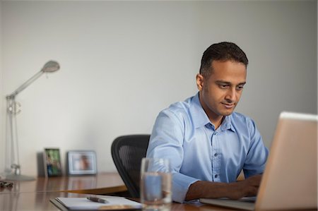 people sitting on desk - Singapore, Businessman working at laptop in office Stock Photo - Premium Royalty-Free, Code: 655-08356914