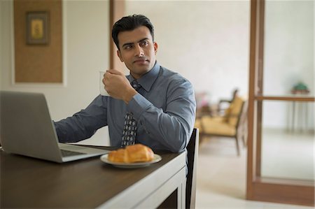 simsearch:614-06898221,k - India, Man holding coffee cup sitting with laptop at home Stock Photo - Premium Royalty-Free, Code: 655-08356988