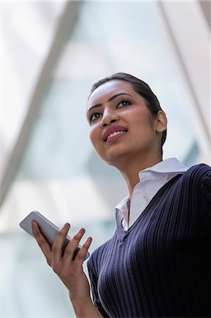 portrait technology bussiness - Young woman standing against glass wall with mobile phone in one hand Photographie de stock - Premium Libres de Droits, Code: 655-08357057