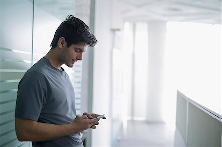 simsearch:655-08357080,k - Young man in office looking down at mobile phone Stock Photo - Premium Royalty-Free, Code: 655-08357061
