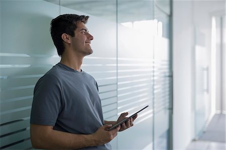 simsearch:655-08357168,k - Young man wearing T-shirt using digital tablet in bright office Photographie de stock - Premium Libres de Droits, Code: 655-08357062