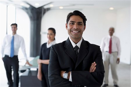 simsearch:655-08357113,k - India, Smiling business man standing with arms crossed in front of colleagues Fotografie stock - Premium Royalty-Free, Codice: 655-08357094