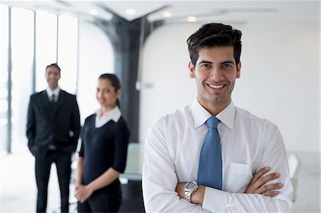 simsearch:655-08357113,k - India, Smiling business man standing with arms crossed in front of colleagues Fotografie stock - Premium Royalty-Free, Codice: 655-08357096