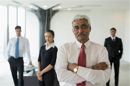 simsearch:655-08357113,k - India, Senior business man standing with arms crossed in front of colleagues Fotografie stock - Premium Royalty-Free, Codice: 655-08357091