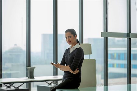 simsearch:655-08357057,k - India, Woman looking up from mobile phone in glass office Photographie de stock - Premium Libres de Droits, Code: 655-08357146