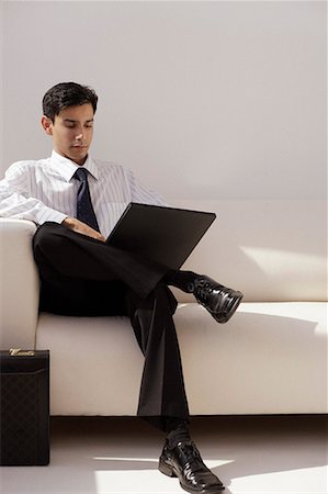 A man sits on a couch with a laptop Stock Photo - Premium Royalty-Free, Code: 655-01781428