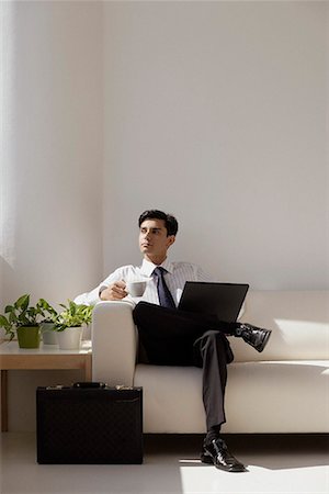 A man sits on a couch with a laptop Stock Photo - Premium Royalty-Free, Code: 655-01781458