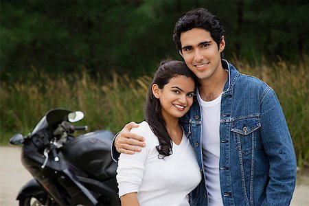Young couple with motorbike smiling at camera Stock Photo - Premium Royalty-Free, Code: 655-01781522