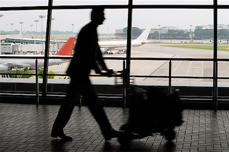 people airports silhouettes - Man pushing trolley at airport Stock Photo - Premium Royalty-Free, Code: 655-01781541