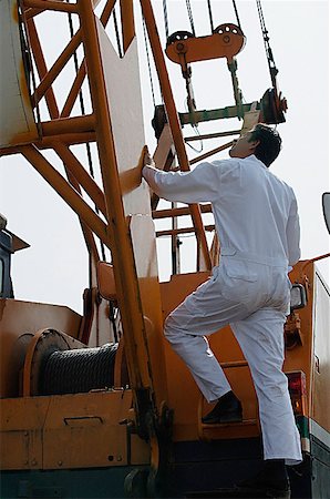 Man in work uniform getting onto crane Stock Photo - Premium Royalty-Free, Code: 655-01781651