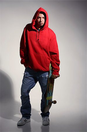 young man wearing red hooded sweatshirt holding skateboard Stock Photo - Premium Royalty-Free, Code: 655-02375809